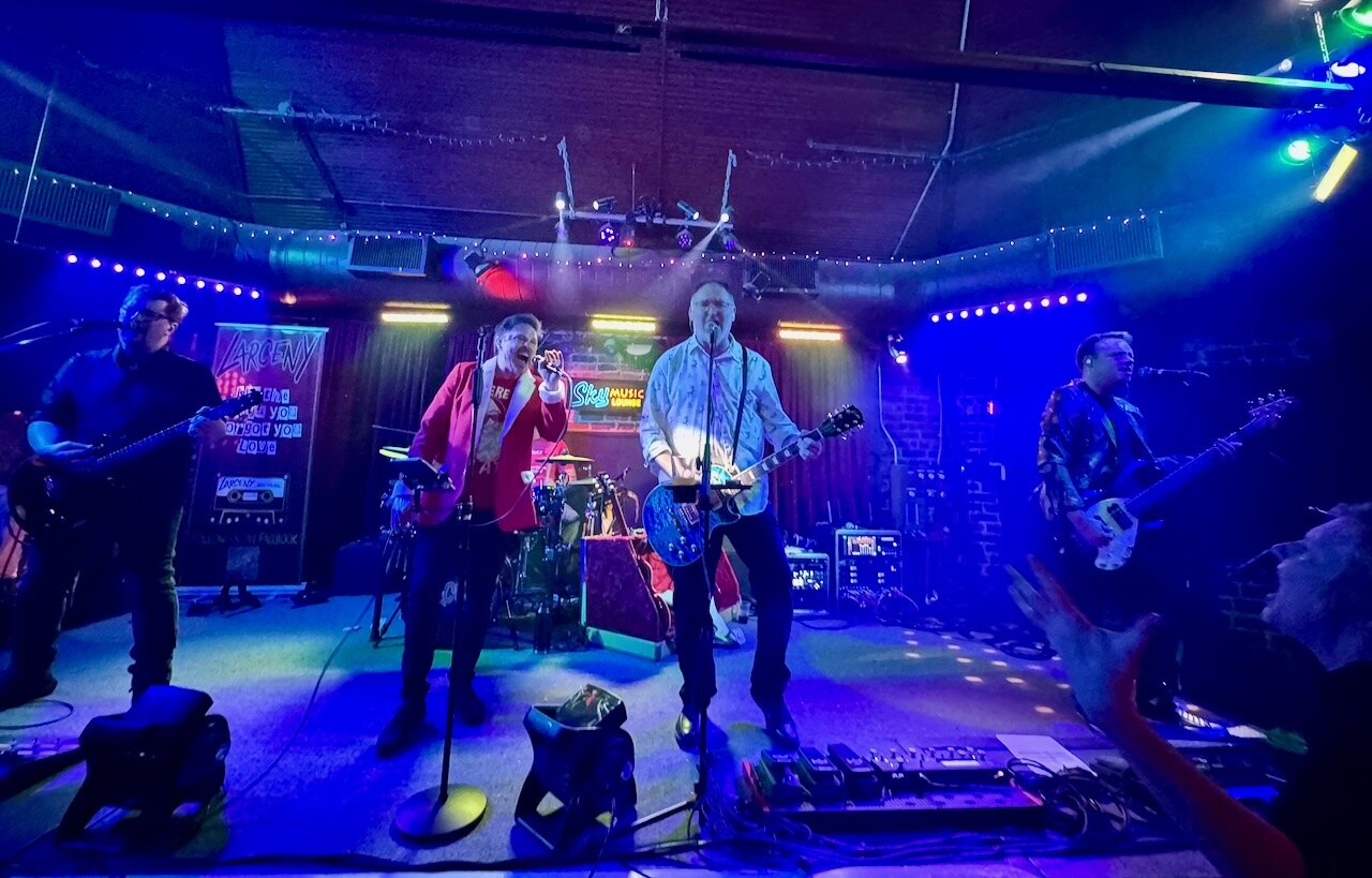 Larceny full band performing on stage at Sky Music Lounge with blue and green lighting