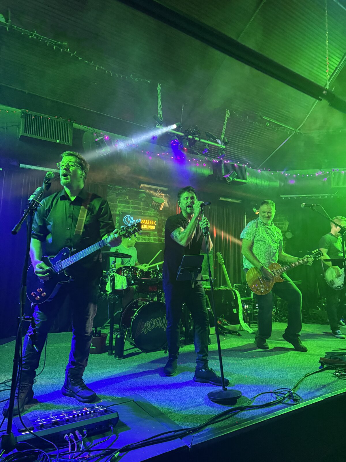 Larceny performing with green stage lights and haze at Sky Music Lounge